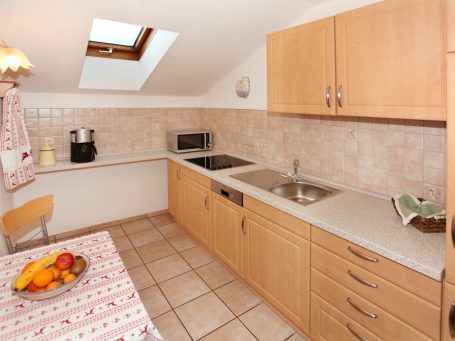 Küche Helle Küche mit Holzschränken, Fliesenboden und Fenster im Dach.